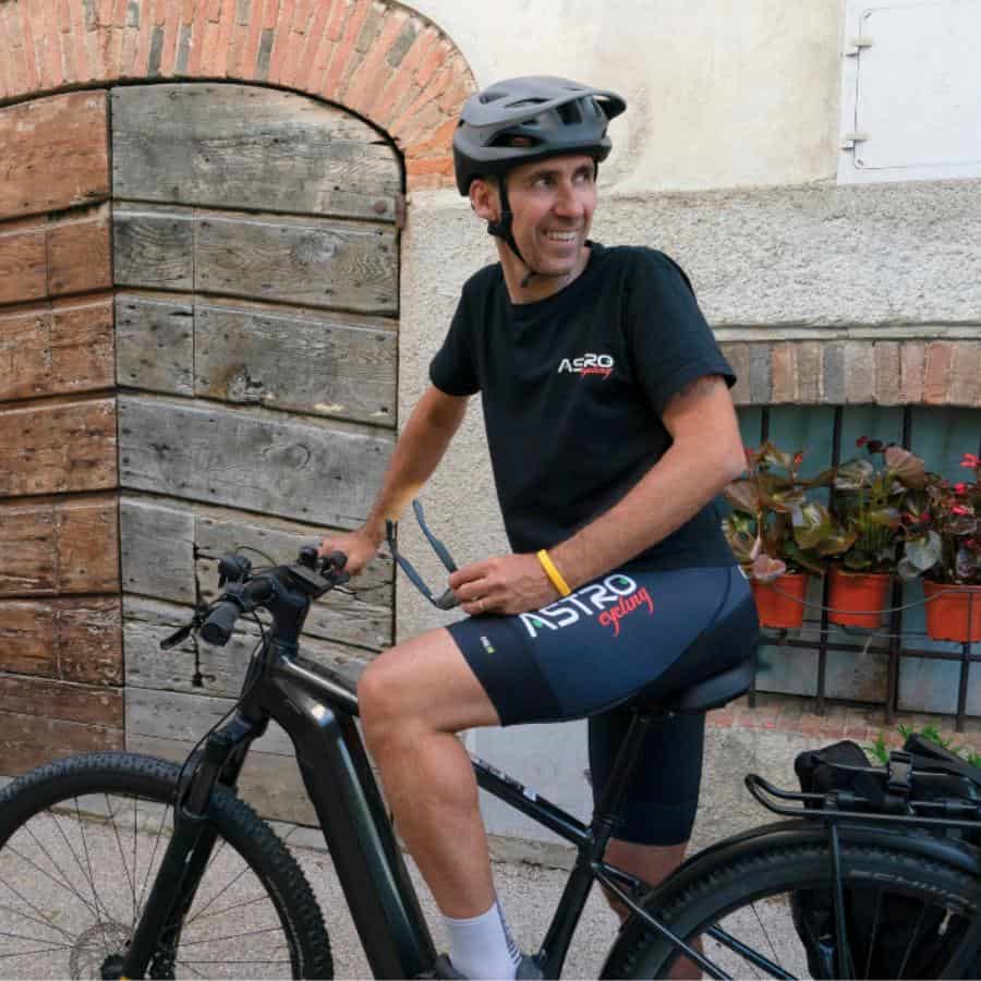 A man stands astride his bike in an Italian town.