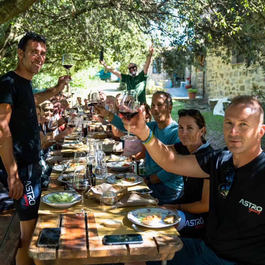 A group of cyclists sit around an outdoor table enjoying lunch
