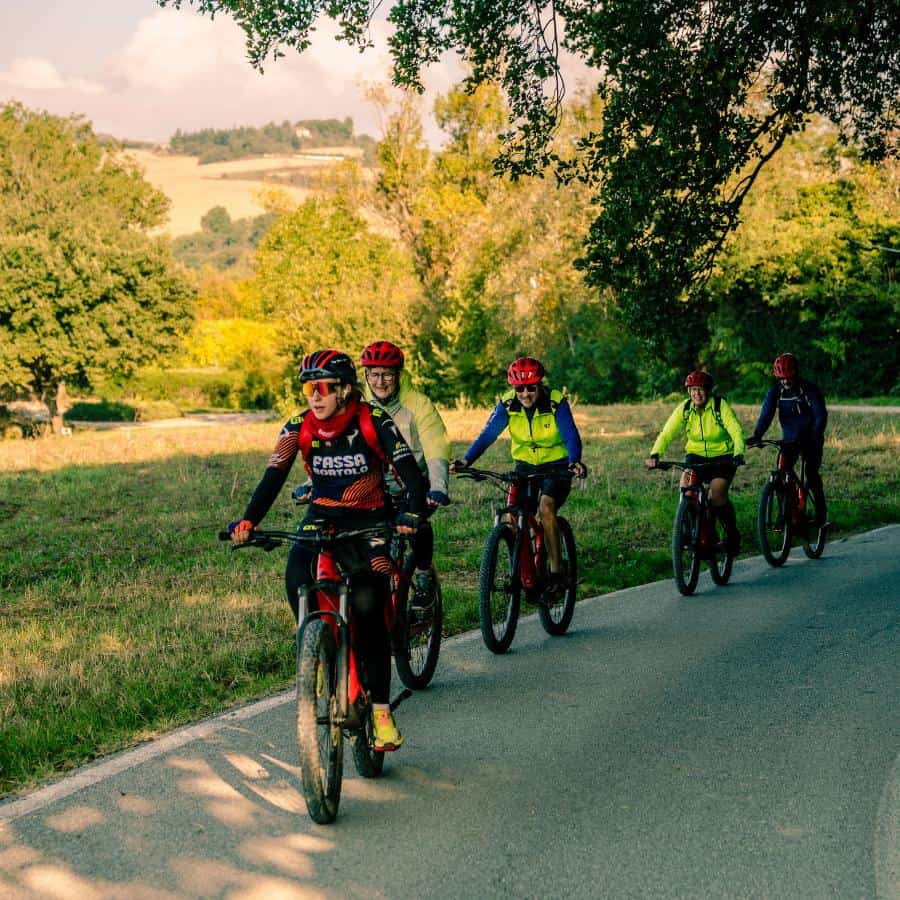 A group of cyclists travel a flat paved road in Italy